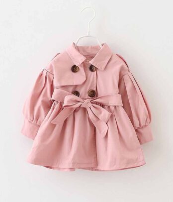 Trench-coat rose chic et confortable pour fillette, avec base évasée, ceinture à nouer et boutons marron. Idéal pour les journées fraîches d’automne.