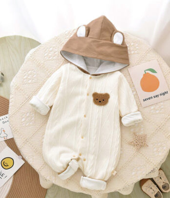 Barboteuse blanche pour bébé en mélange de coton, avec capuche marron ornée de petites oreilles, boutons-pression à l’avant et style mignon et confortable pour les journées cocooning.