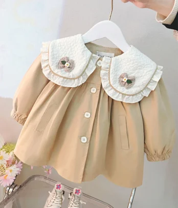 Robe beige style trench-coat avec col Claudine décoré de papillons. Légère, élégante et confortable, elle offre une liberté de mouvement idéale au quotidien.