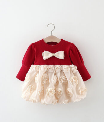 Robe enfant bicolore rouge et blanc cassé à manches longues, col rond, jupon à fleurs en relief et nœud papillon décoratif sur le devant.