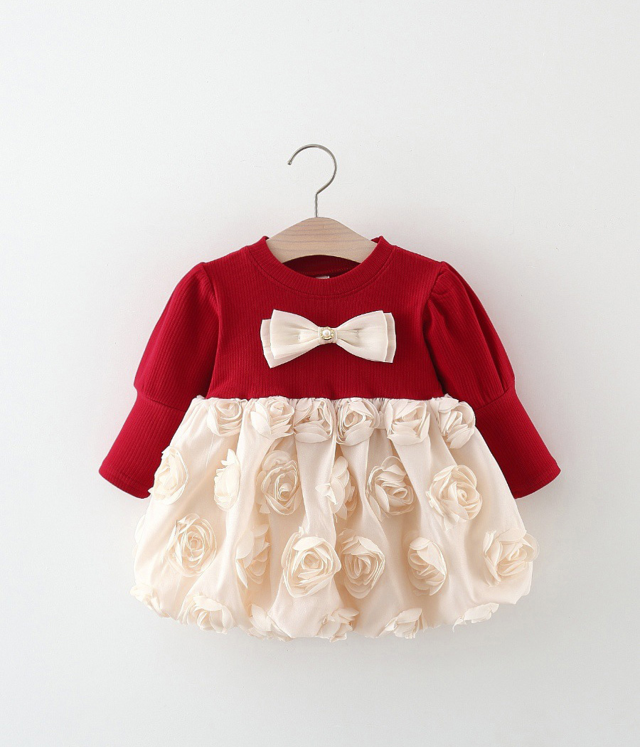 466411 Robe enfant bicolore rouge et blanc cassé à manches longues, col rond, jupon à fleurs en relief et nœud papillon décoratif sur le devant.