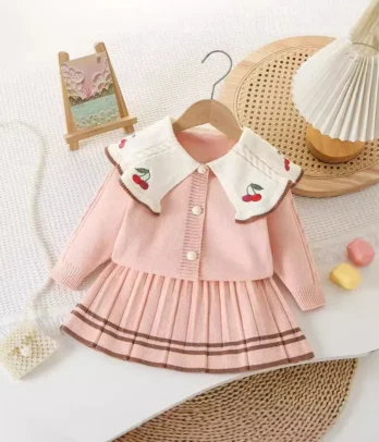 Set adorable avec jupe plissée fluide et cardigan à col brodé de cerises, mêlant élégance et fantaisie pour un look confortable et plein de charme.