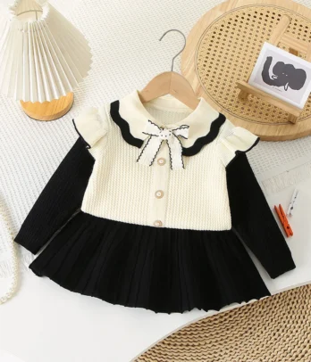 Ensemble chic avec pull-over blanc cassé à manches noires et jupe noire évasée, pour un look élégant, confortable et intemporel au quotidien.