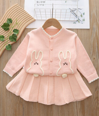 Ensemble rose avec cardigan brodé de lapins et jupe plissée fluide, alliant douceur, confort et charme pour toutes les occasions.