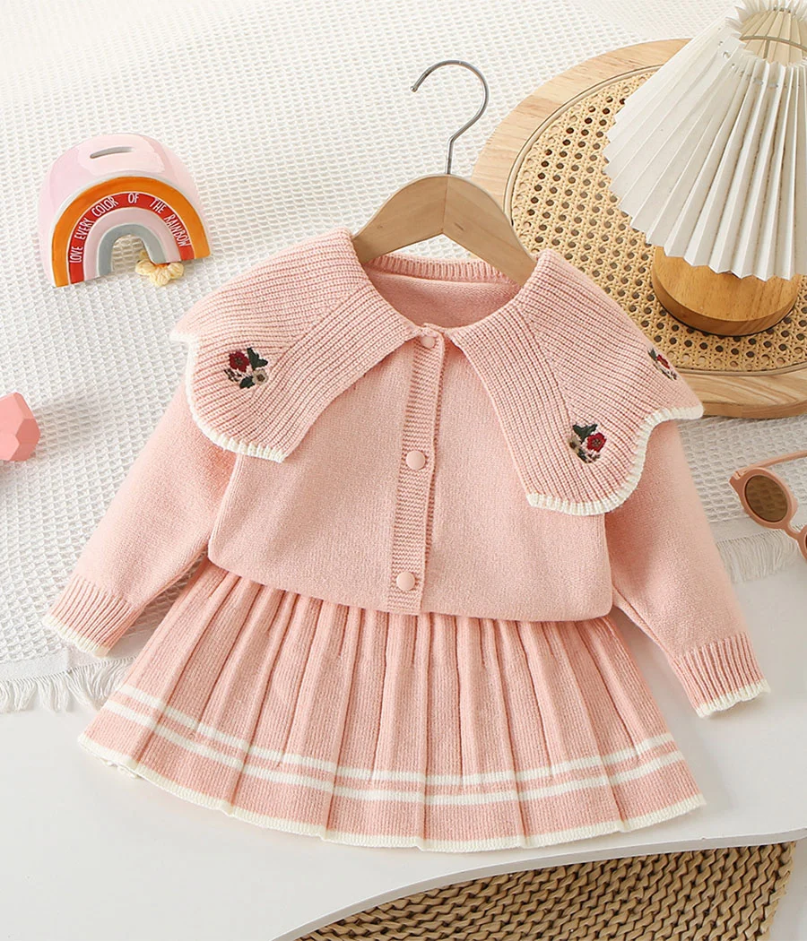 67784 Ensemble élégant avec jupe plissée rose et cardigan à col brodé de fleurs, confortable et raffiné, parfait pour la mi-saison, les fêtes ou l’école.