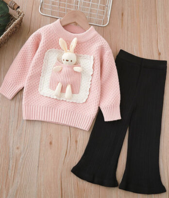 Ensemble enfant avec pull-over rose en maille douce orné d’un motif lapin brodé, finitions côtelées, assorti à un pantalon noir patte d’éléphant à taille élastiquée et coupe évasée rétro.