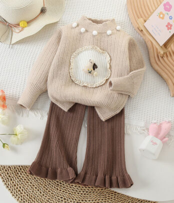 Ensemble enfant avec pull en laine crème à col rond orné de pompons et motif lapin, assorti à un pantalon marron coupe cloche à taille élastiquée, confortable et tendance pour l’automne.