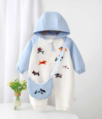 Barboteuse imperméable pour bébé avec capuche, imprimé joyeux de petits chiots colorés sur fond bleu et blanc, tissu coupe-vent avec doublure douce, fermeture zippée et à pressions, finitions élastiques pour confort et protection par temps de pluie.