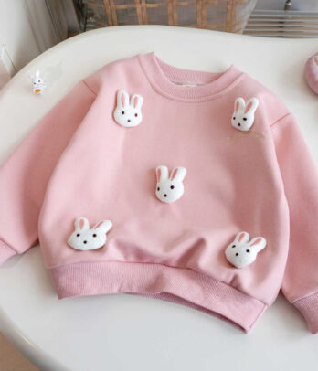 Pull-over enfant en maille blanc rosé, col rond et finitions côtelées, orné de petits lapins en relief cousus à l’avant. Doux, chaud et confortable, idéal pour l’hiver et les looks cosy.