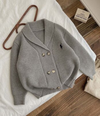 Cardigan garçon en tricot gris clair de style old money, avec col en V, broderies fines, boutons discrets et maille douce. Élégant et intemporel, idéal pour les occasions spéciales ou un look chic au quotidien.