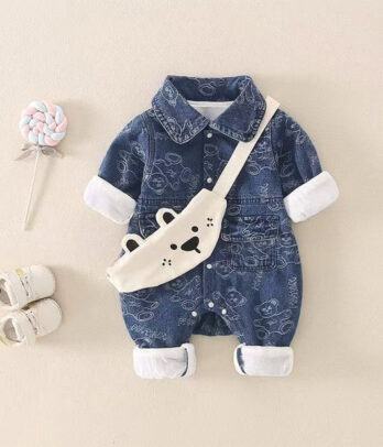 Combinaison bébé en jean foncé avec imprimés modernes, petite sacoche intégrée façon bandoulière à l’avant, bretelles et boutons-pression pour un style streetwear confortable et pratique.