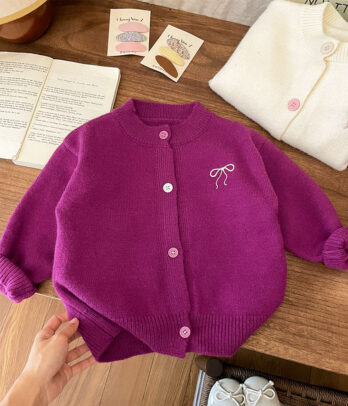 Cardigan pour fille en maille douce de couleur fuchsia, avec col rond, boutons élégants sur le devant, finitions côtelées et petite broderie en forme de nœud papillon sur le côté.