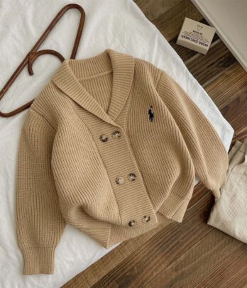 Cardigan pour garçon en tricot doux de style old money, avec col en V, boutons discrets marron dégradé, broderies délicates et finitions soignées. Modèle élégant et intemporel, parfait pour les occasions spéciales ou un look chic au quotidien.