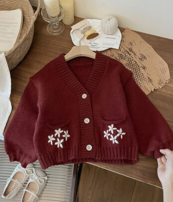 Cardigan enfant en tricot crochet rouge avec broderies décoratives sur les poches, coupe confortable et fermeture boutonnée sur le devant.