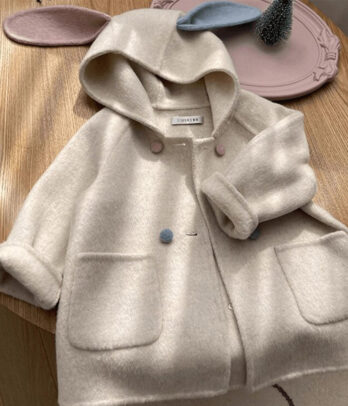 Manteau en laine pour fille à coupe évasée avec capuche ornée d’oreilles de lapin, boutons sur le devant et coloris pastel. Chaud, doux et adorable, idéal pour l’hiver et les sorties enchantées.