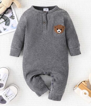 Barboteuse bébé grise unie en tissu doux et respirant, coupe ample décontractée avec ouverture à boutons-pression, style minimaliste et confortable pour un usage quotidien.