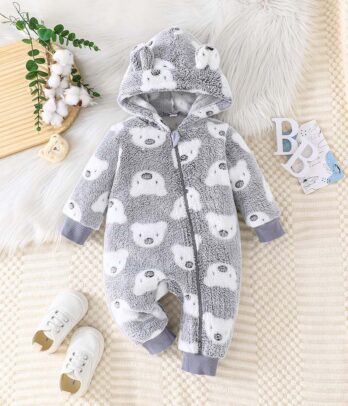 Barboteuse bébé en fourrure douce effet peluche avec imprimé de petits doudous, capuche intégrée, intérieur rembourré et fermeture zippée à l’avant, manches et chevilles resserrées pour l’hiver.