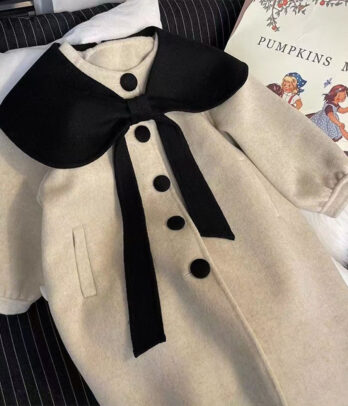 Manteau beige en cachemire avec col noir contrastant, doux et chaud, alliant élégance et confort pour les sorties habillées et les journées fraîches.