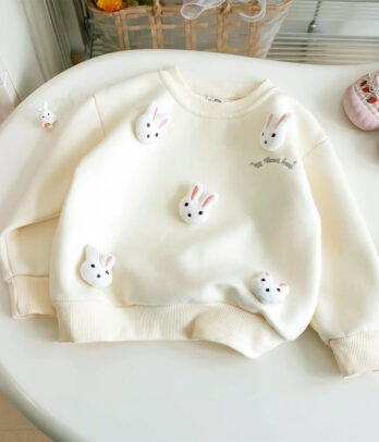 Pull-over pour enfants en maille blanc cassé, col rond et finitions côtelées, orné de petits lapins en relief cousus à l’avant. Doux, chaud et confortable, parfait pour l’automne et l’hiver.