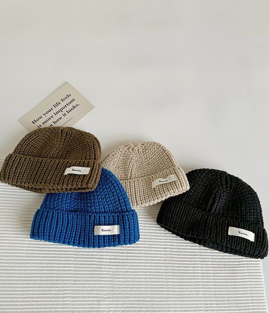 87944 (9) Bonnet d’hiver en laine douce avec revers et étiquette décorative, idéal pour garder les enfants bien au chaud avec style lors des journées froides.