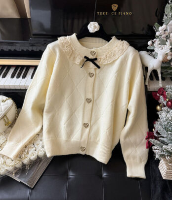 Cardigan fille style Chanel en maille blanc cassé avec col rond volanté, nœud noir, boutons décoratifs et bordures contrastées, coupe droite élégante et confortable.