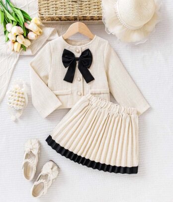 Ensemble style Chanel pour fillettes avec veste courte en tweed à boutons dorés et jupe plissée assortie, pour un look chic lors des fêtes ou cérémonies.