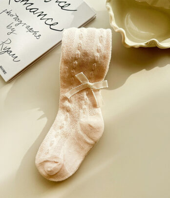 Bas collant beige pour enfant avec petit nœud décoratif à la cheville, tissu doux et extensible, coupe ajustée idéale pour les tenues élégantes.