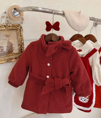 Manteau pour enfant en velours rouge profond avec col montant à nouer, fermeture boutonnée, doublure intérieure et coupe légèrement évasée.