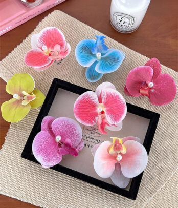 Orchidées colorées à porter en barrette ou broche, apportant une touche florale chic et vibrante aux coiffures ou aux tenues pour toutes les occasions.