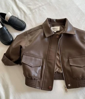 Veste enfant en simili cuir marron, coupe droite ample, col chemise, fermeture zippée, poches à rabat et revers aux manches, douce et résistante pour la mi-saison.